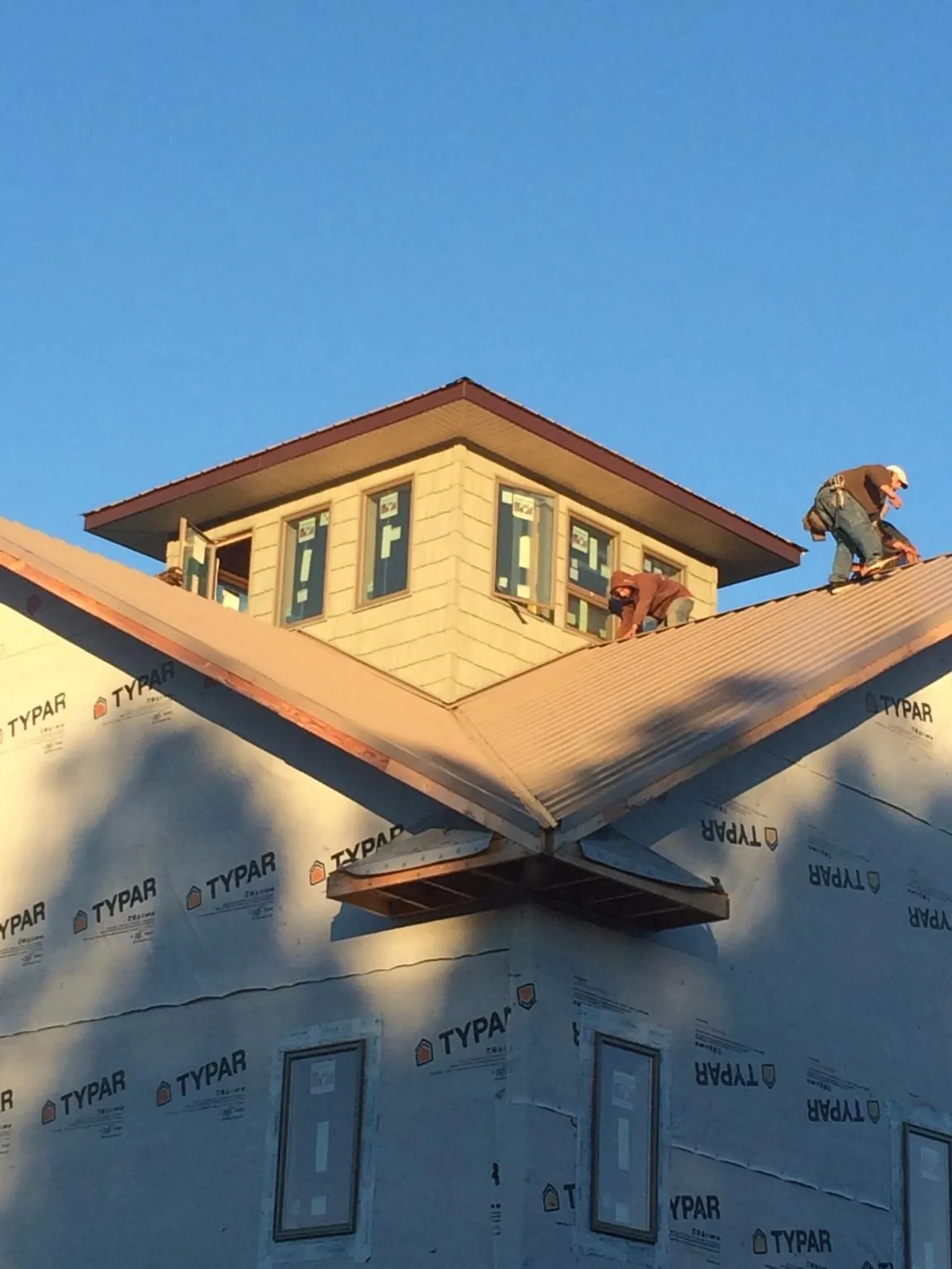 Roofers working around a rooftop cupola on a new metal roof at sunset — Roof Waterproofing in Elkton by Roofing Brothers